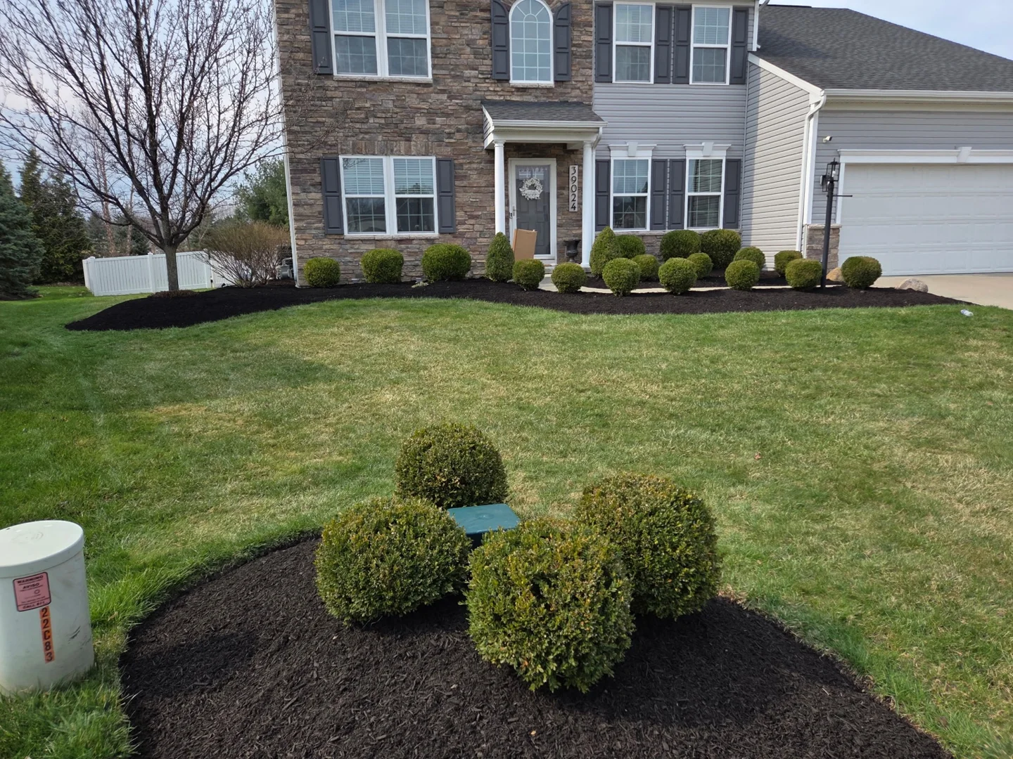 Fresh dark mulch and neatly shaped beds around a front lawn