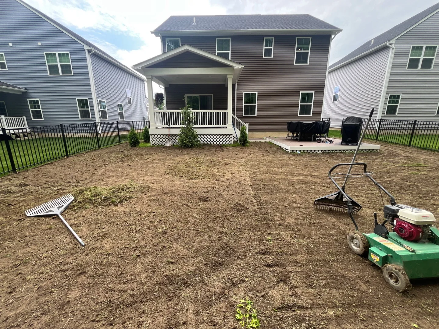 Lawn renovation in progress with preparation equipment in a fenced backyard