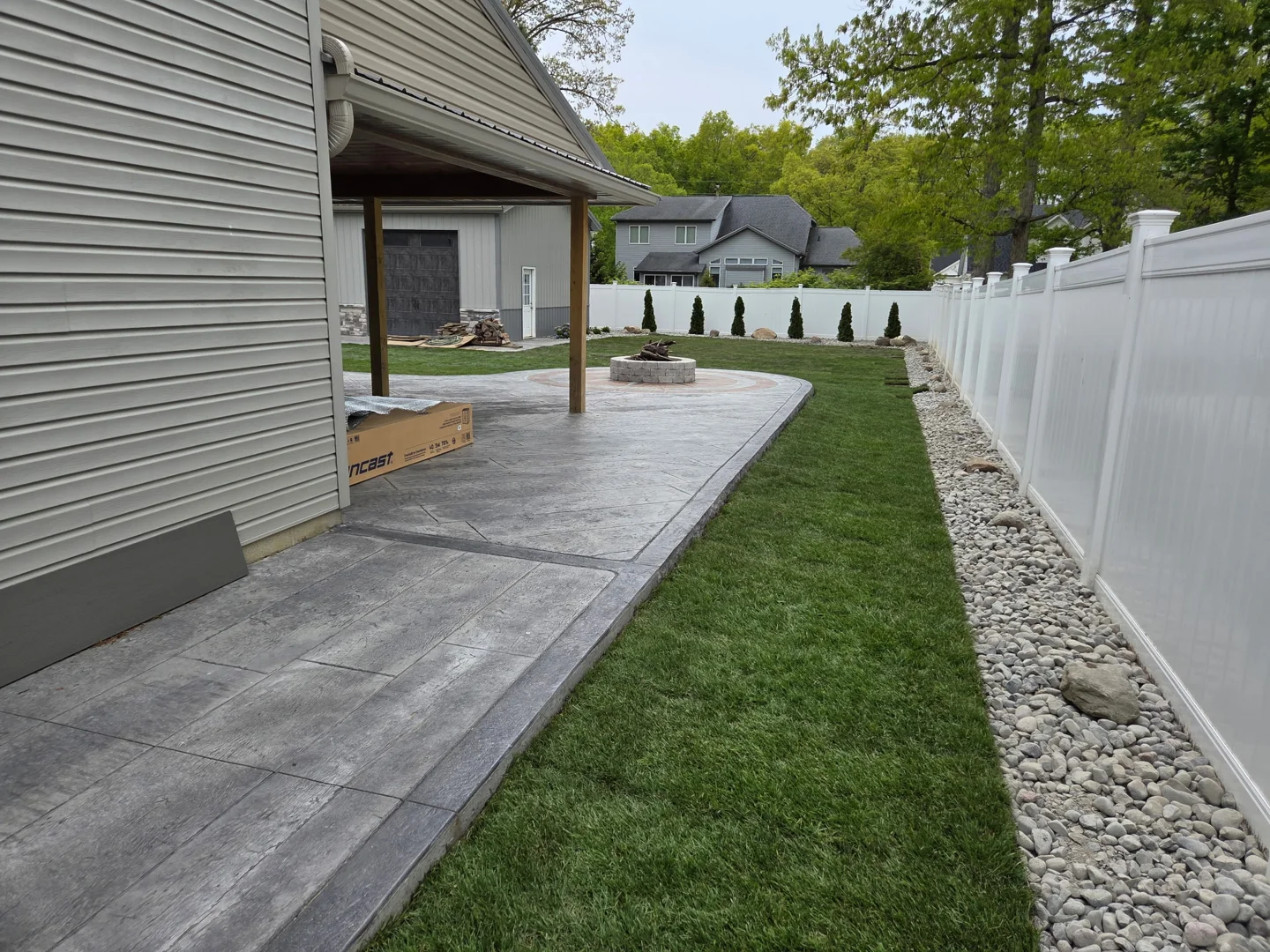 New lawn and decorative stone border beside a backyard patio